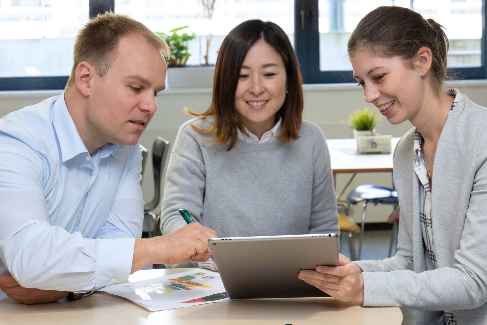 Besprechungssituation drei Personen am Tisch mit Tablet
